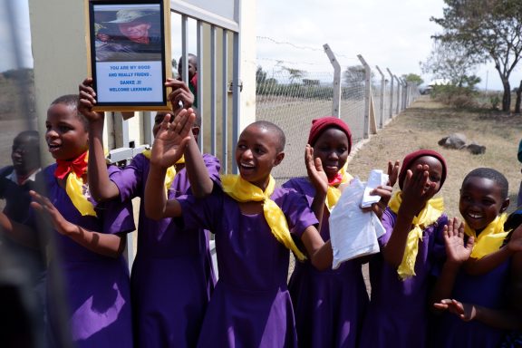 6 Schülerdelegation vor dem Eingangstor Sechs Kinder stehen jubelnd vor dem Zaun. Ein Kind hält ein Schild hoch: You are my good and really friend. Danke!!! Welcome Lekrimun