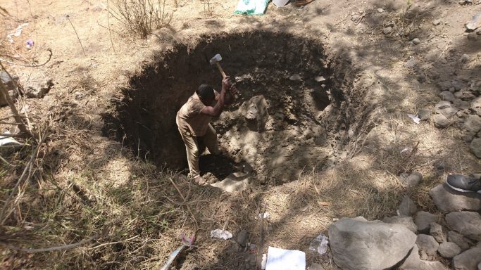 2 erste Arbeiten Ein Mann schwingt einen Hammer um Steine in der Grube klein zuschlagen