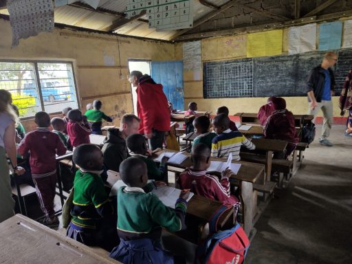 2 Innerhalb eines Klassenraums Mehrere Kinder sitzen in Reihen vor einer Tafel.