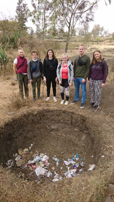 1 Aus einer Grube für Abfall wird ein Brunnen (Herbst 2022) Sechs Menschen stehen um eine Grube mit Abfall
