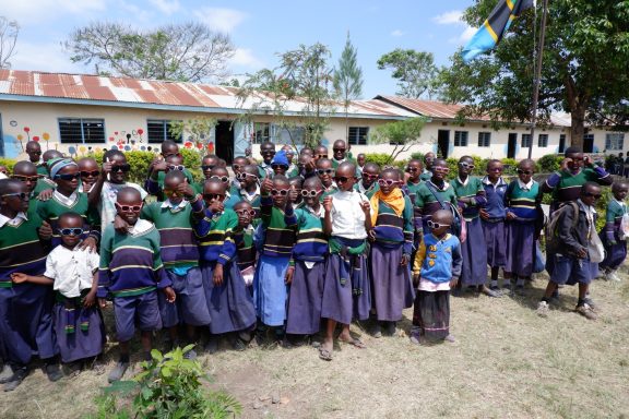 6 Gruppenbild mit dm-Sonnenbrillen Ca. 30 Kinder mit Sonnenbrillen stehen in einer Gruppe und zeigen einen Daumen hoch.