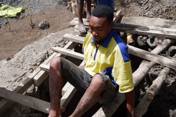 6 ...einfachen Mitteln Ein Mann hockt über dem Loch auf mehreren Latten.