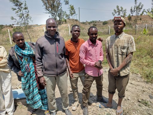 2 Massai, die den Brunnenbau organisieren Eine Gruppe von fünf Männern die den Brunnen organisiert haben.